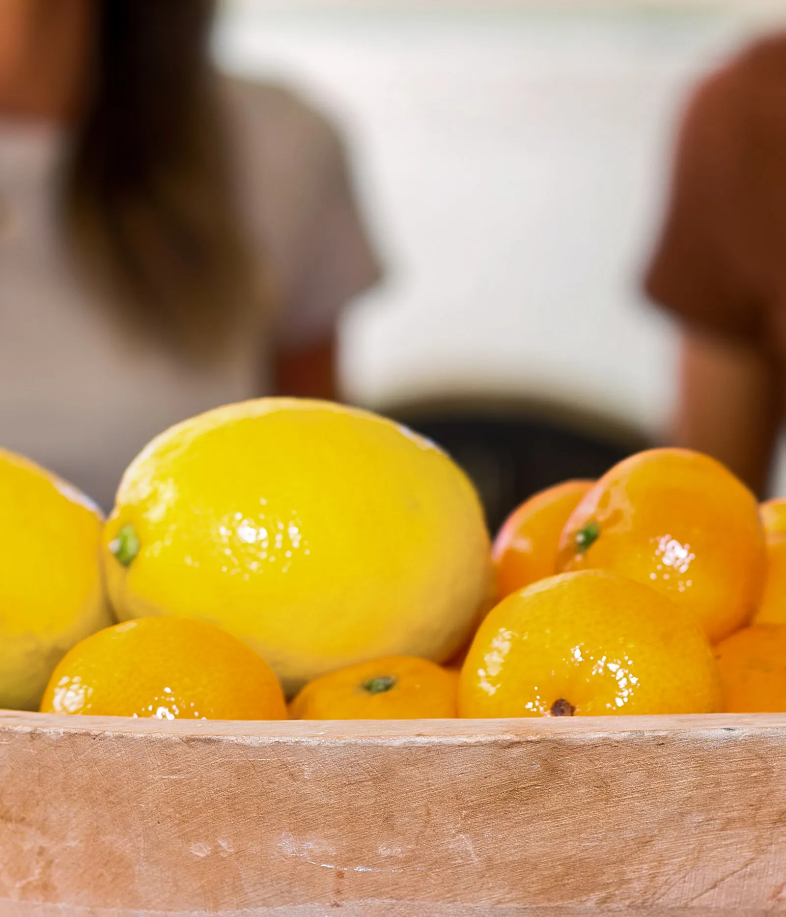 A wooden bowl of lemons and tangerines on a kitchen counter