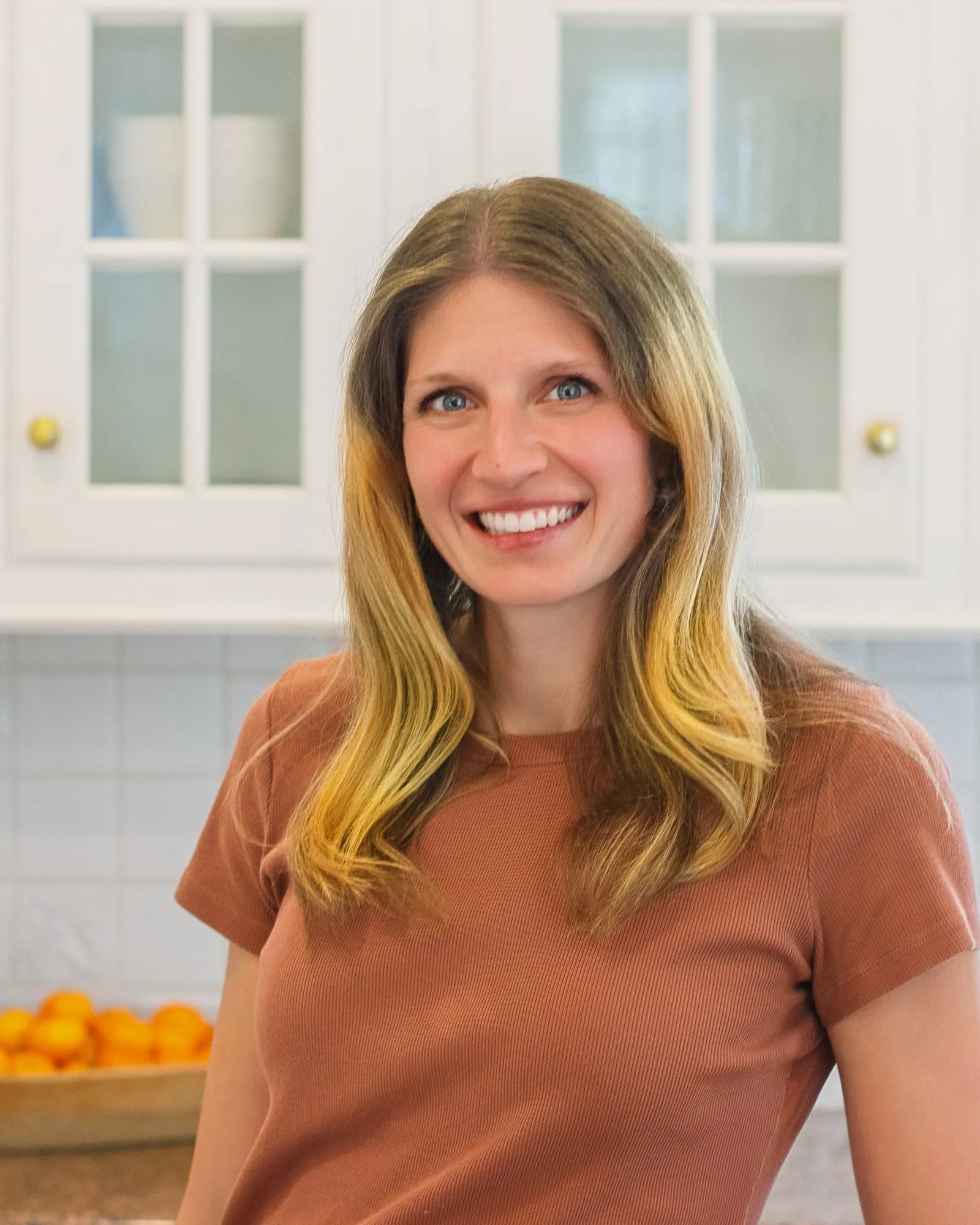 Kelsey Shaughnessy, RDN, in a bright kitchen with oranges on the counter behind her