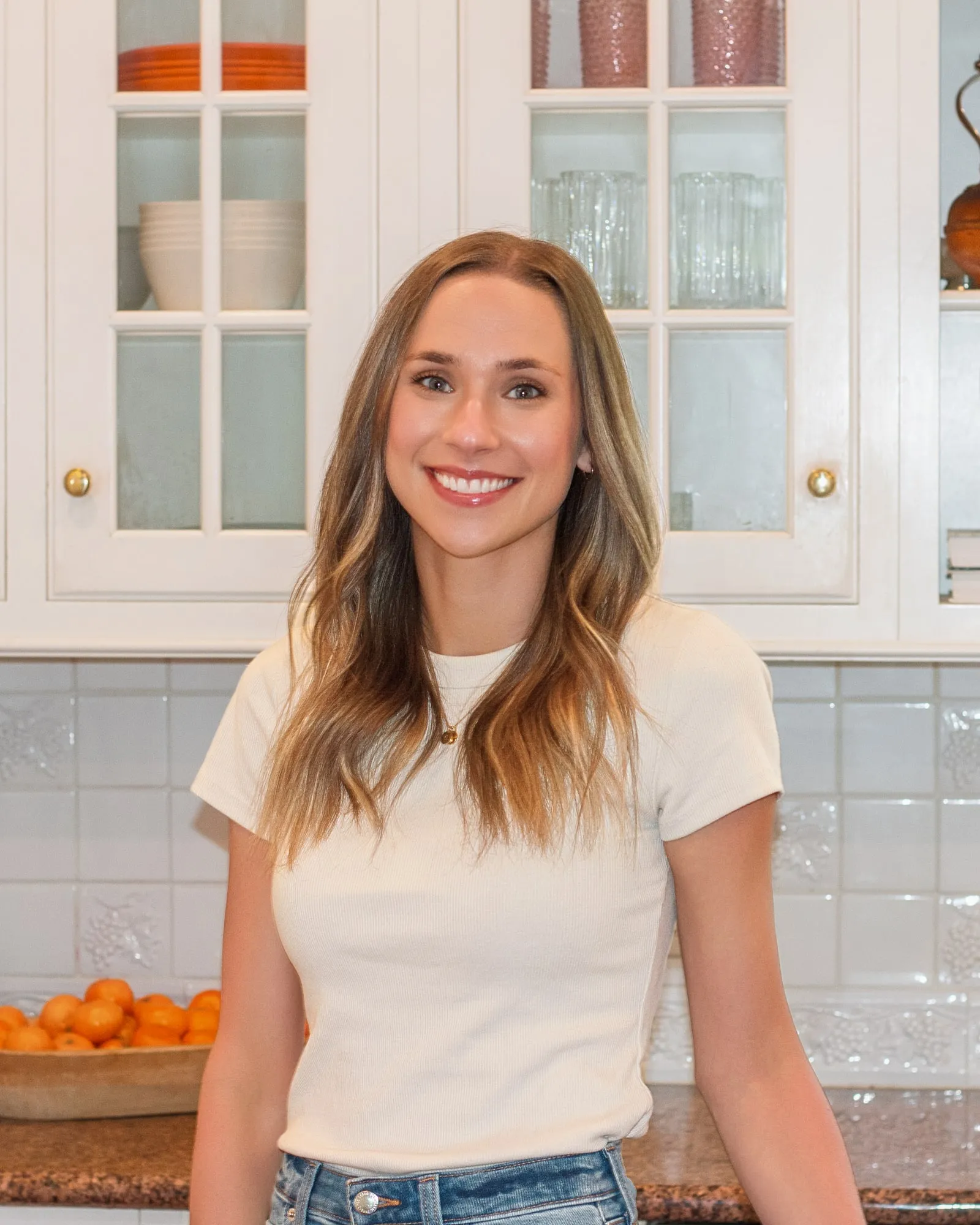 Macie Fuquay, RDN, in a bright kitchen with oranges on the counter behind her