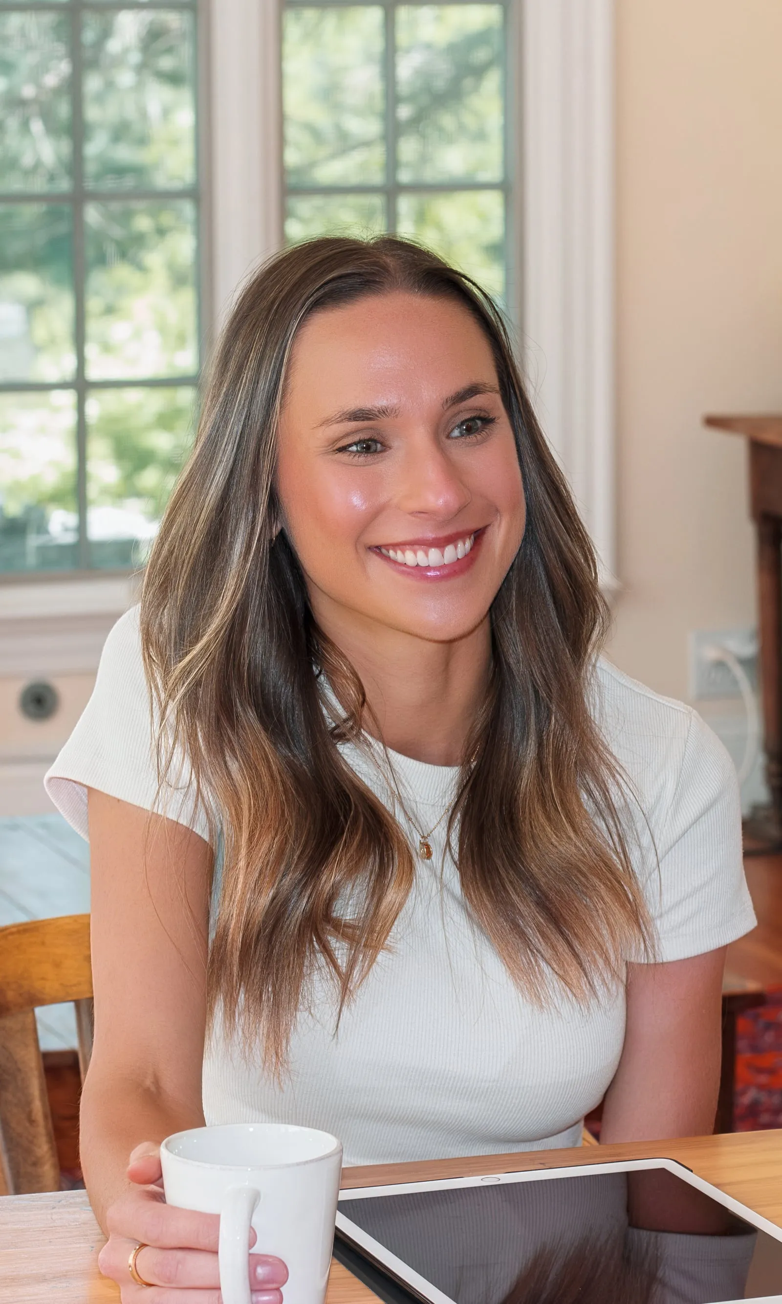 Macie Fuquay, RDN, smiling during a session with a client at a table in a sunny living room